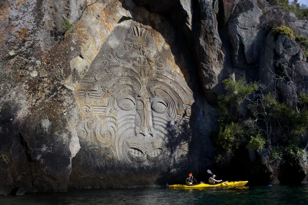 Kayakers visit the Maori rock carvings at Mine Bay