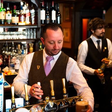 Bartenders pour up a particularly smooth pint of Guinness at The Guinea.