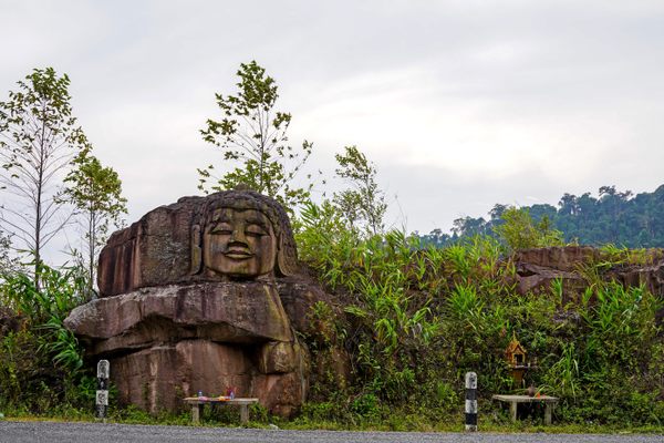 A large reclining Buddha is carved into sandstone along the side of the Thakhek Loop.