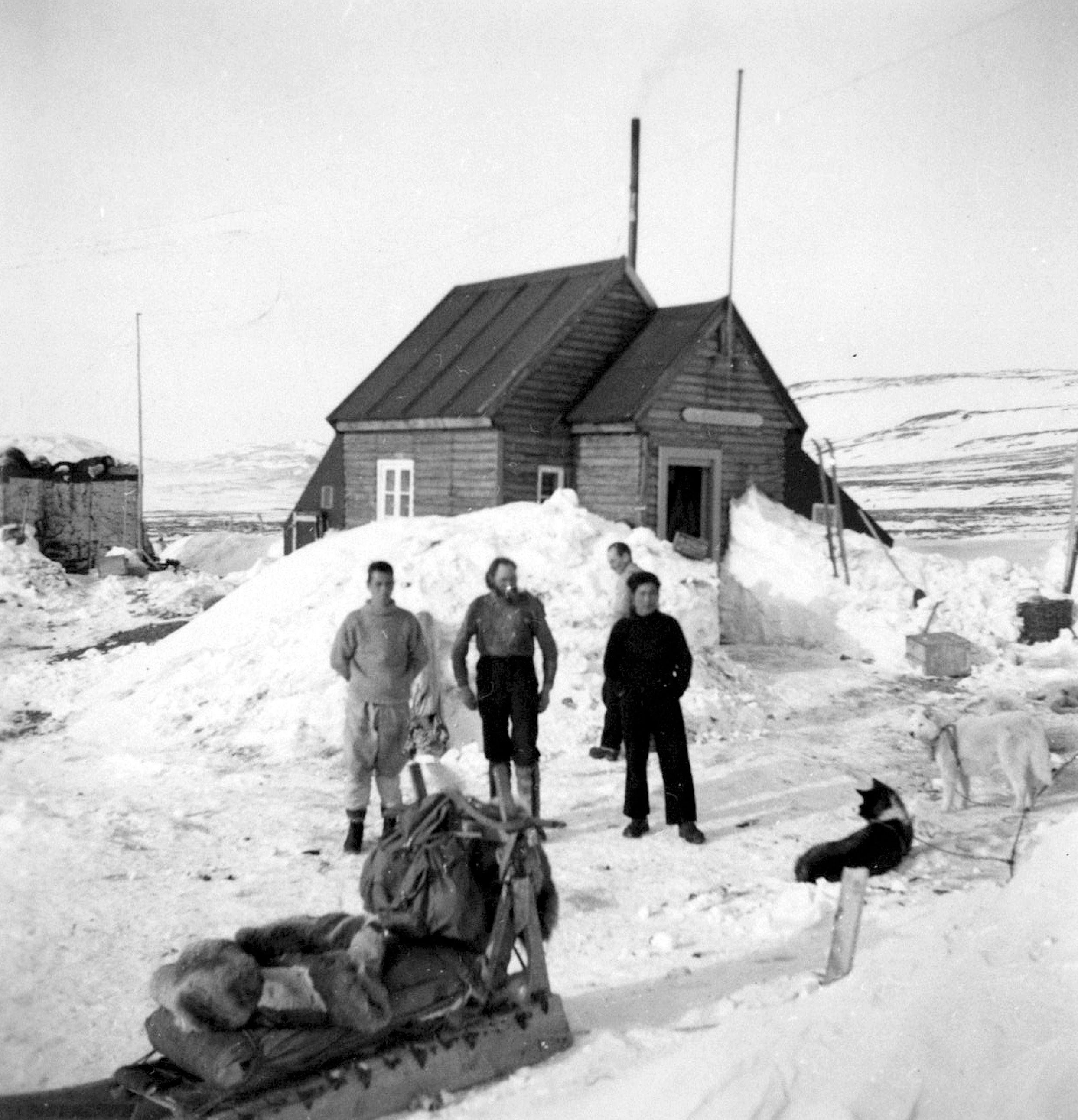 Eli Knudsen, Bendt Jensen, and Petrus Pêke rest with their dogs at a hunting station.